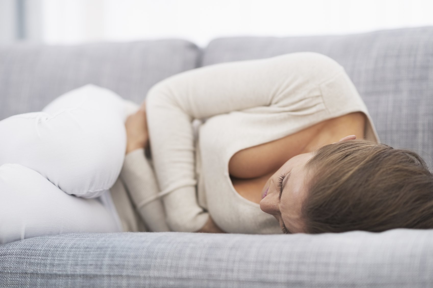 a young woman lying on the sofa feeling nauseas