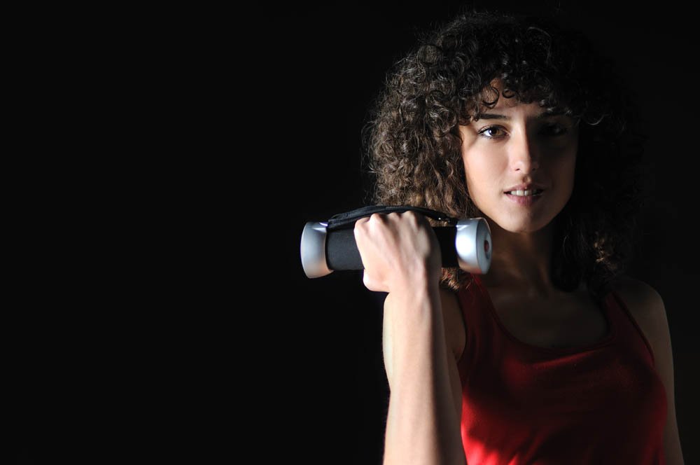 young woman practicing fitness and working out in a gym with dumbbell, weight lifting concept.