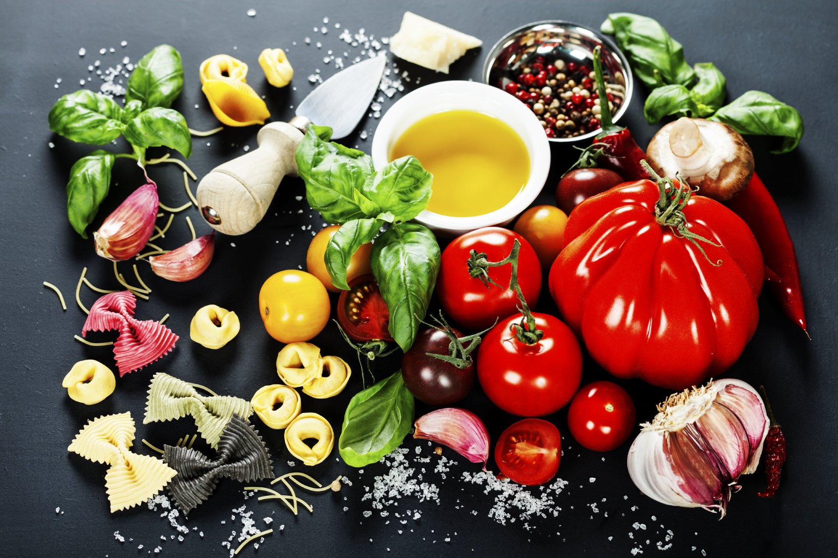 mediterranean diet ingredients: garlic, tomatoes, oil, pasta, basil, olives, herbs