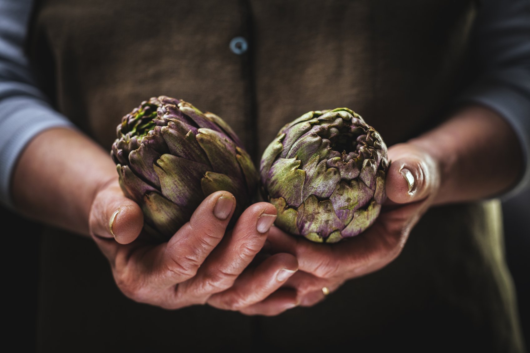 a woman holds two artichokes in her hands
