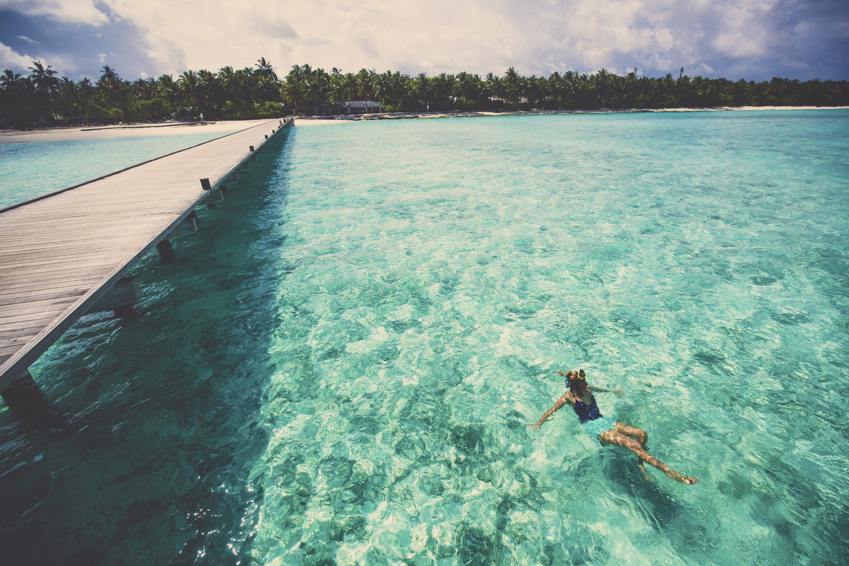 Photo of young woman swimming next to the main entrance of one of the tropical islands of Maldives